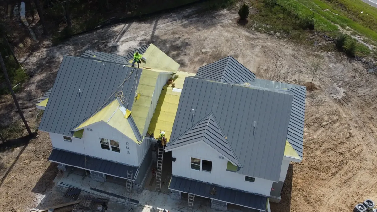 Aerial of gray standing seam metal panels on a coastal Georgia building, with the Coastal Roofworks crew on the roof