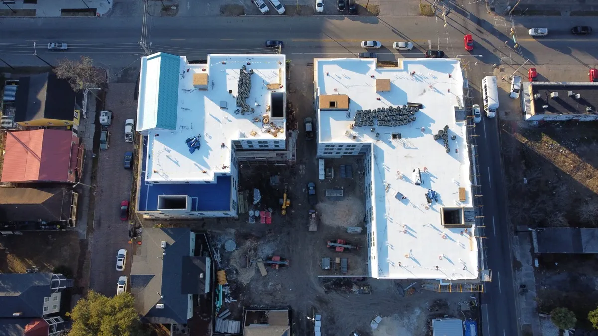 Two commercial buildings with white TPO roofs, aerial view